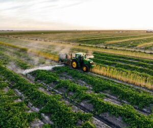 Green tractor spraying fertilizer on a field